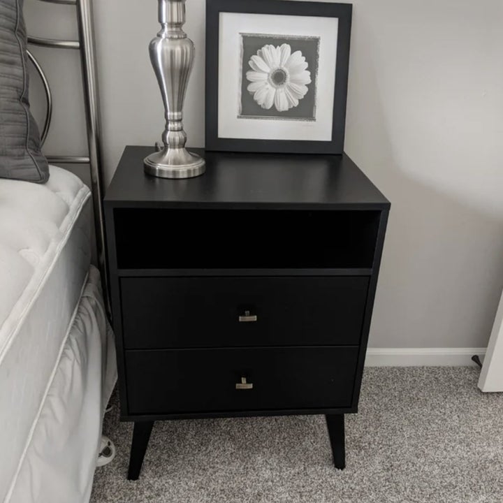 A reviewer's black two drawer nightstand next to a bed
