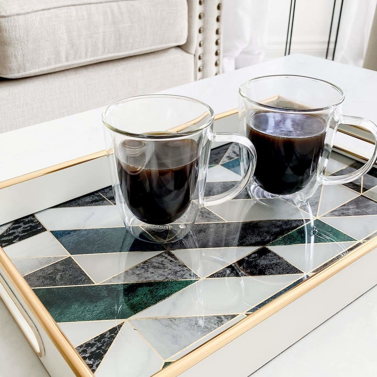 Two glass mugs of coffee on marble tray