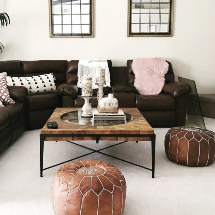 A reviewer's set of round tan leather poufs in front of a couch 