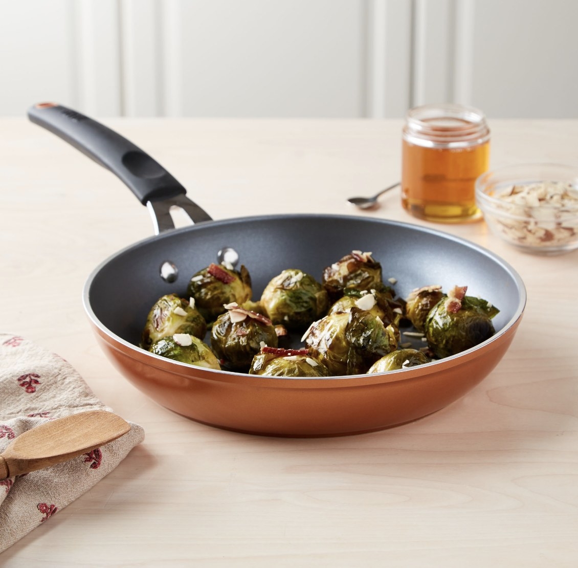 The copper pan is holding roasted Brussels sprouts and is surrounded by other cooking supplies