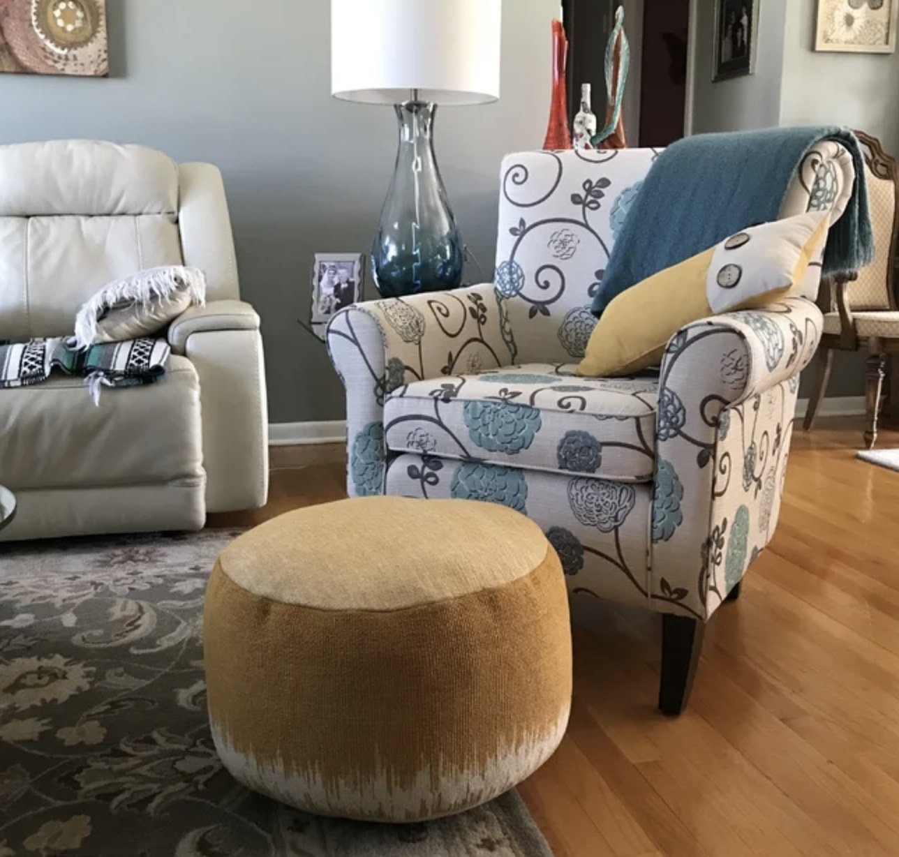 A reviewer&#x27;s orange abstract print round pouf in a living space