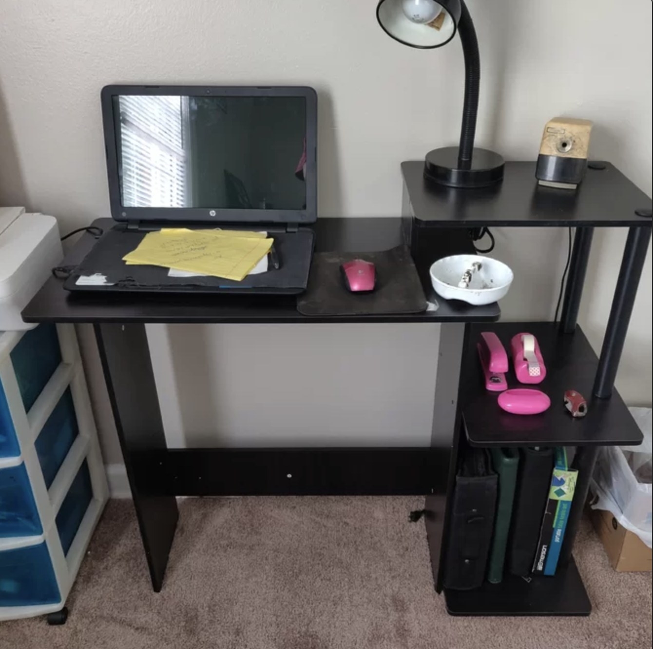 A reviewer&#x27;s black desk with books and a laptop and desk essentials on it 