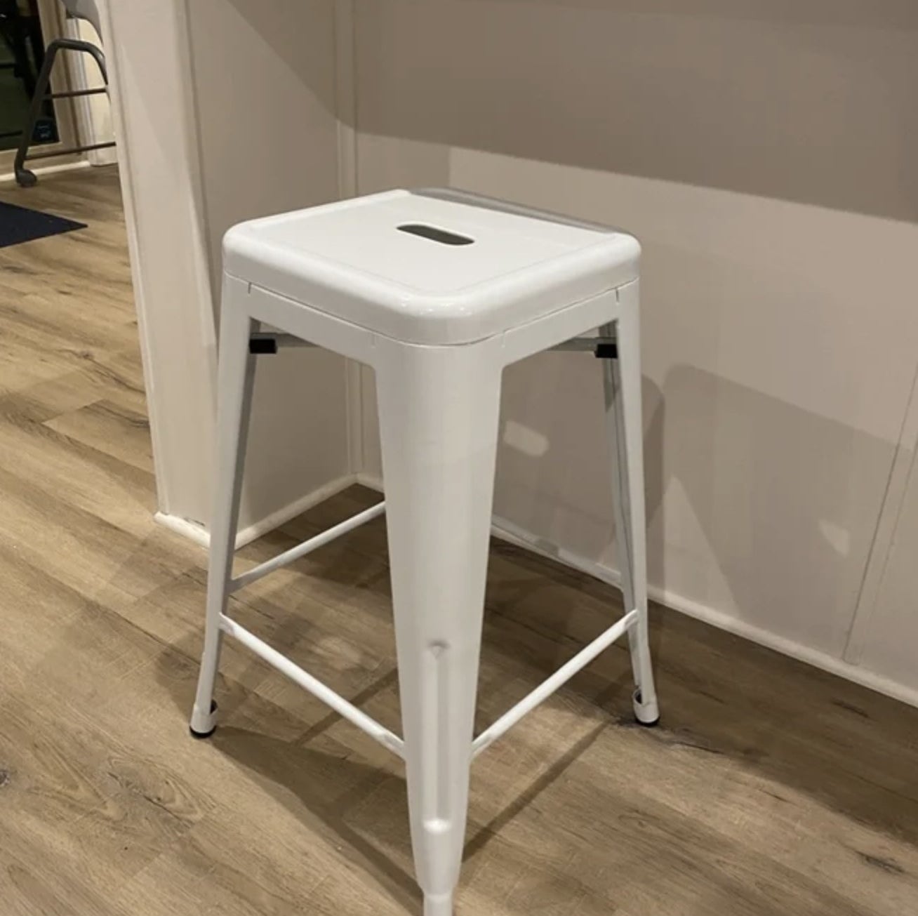 A reviewer&#x27;s white metal backless bar stool in front of a kitchen counter 