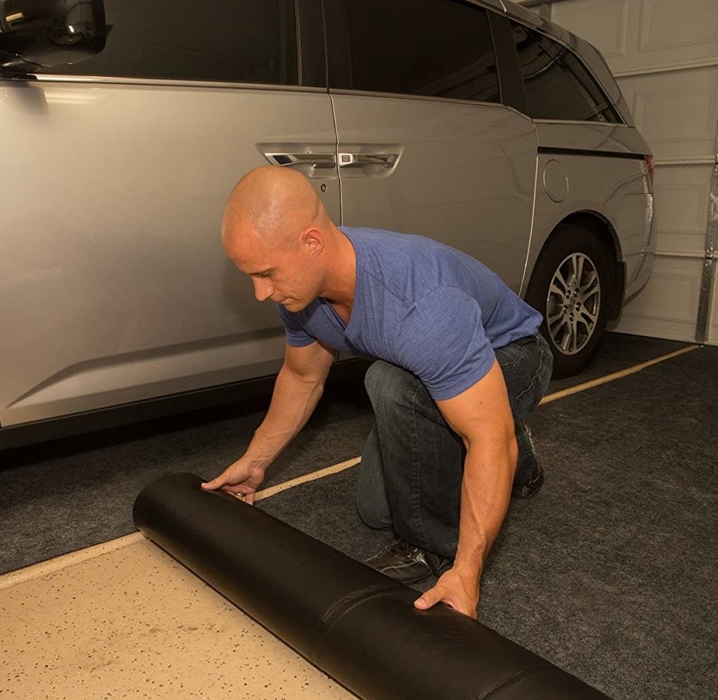 A person putting down the mat in their garage