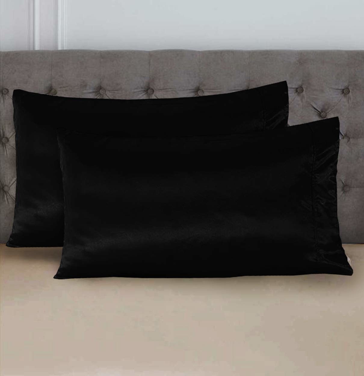 Two full-black satin pillow covers on a bed. 