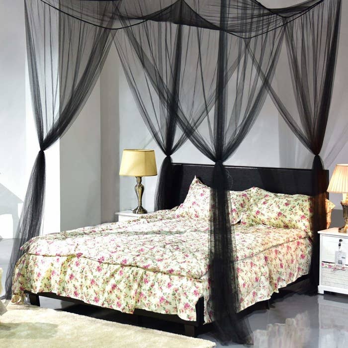A black canopy mosquito net placed around a bed.