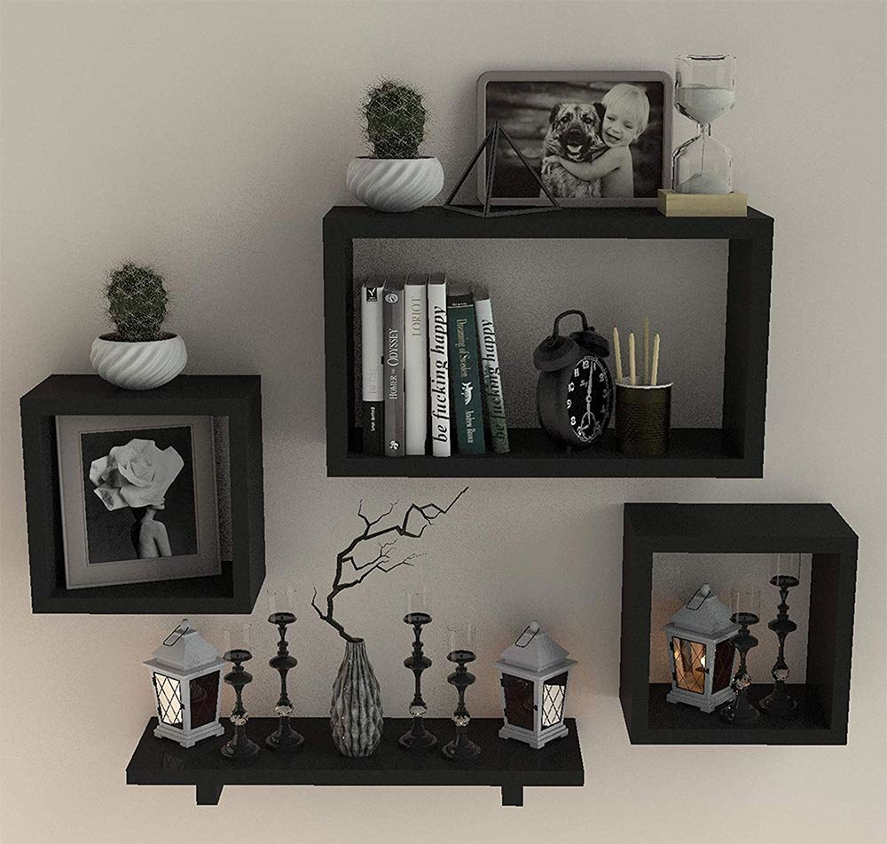 A set of 4 shelves; 1 plank, 2 square and 1 rectangular, hang on a wall with decorations on them. 
