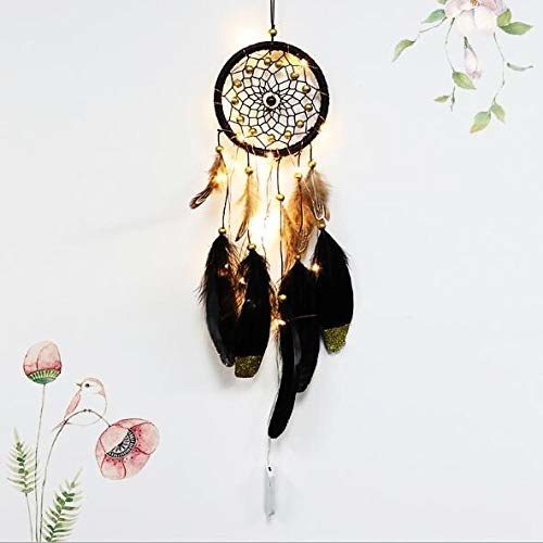 A black dreamcatcher with warm-toned LED lights hangs on a white wall.