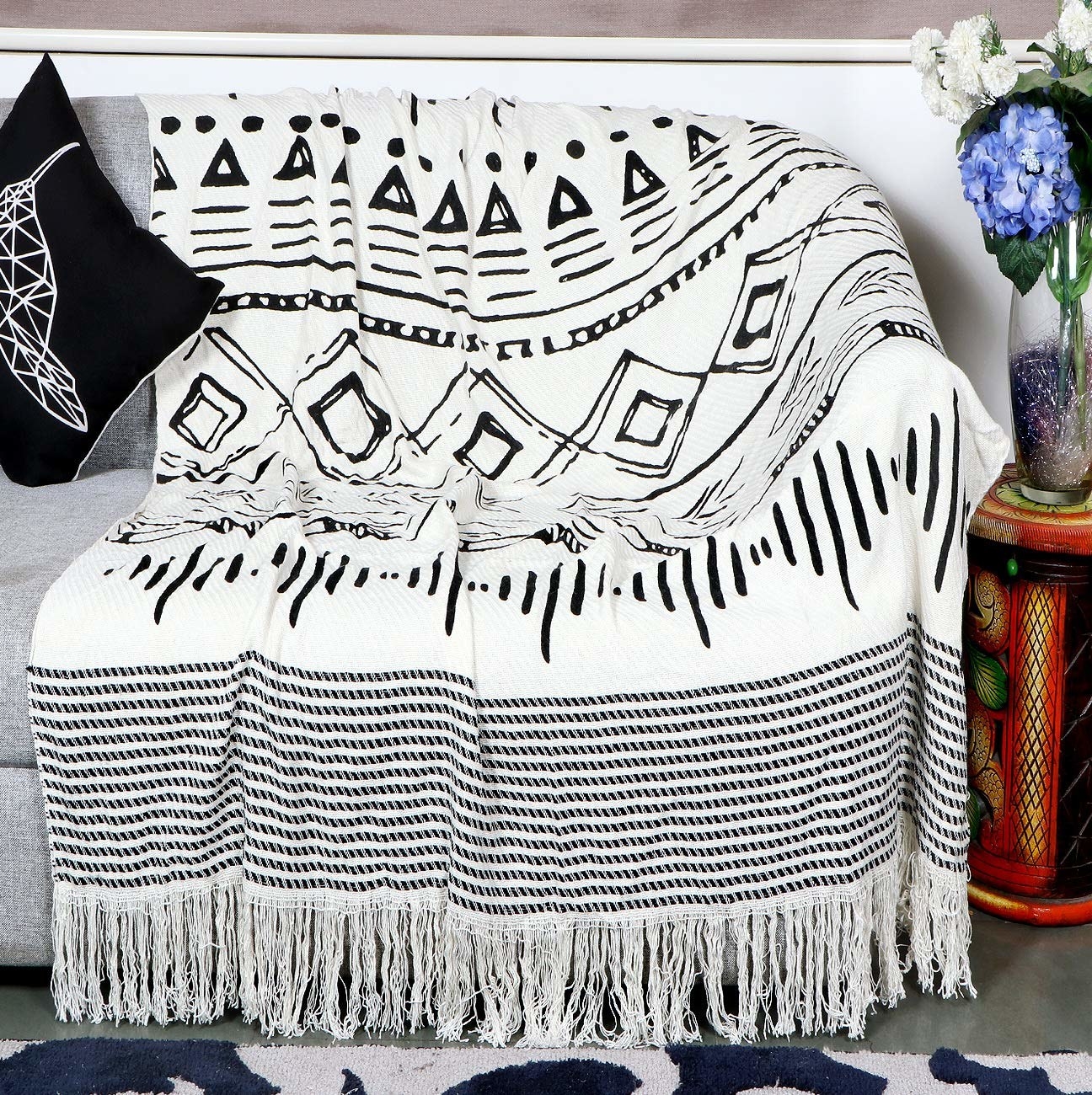 A black and white sofa throw placed on a grey sofa.