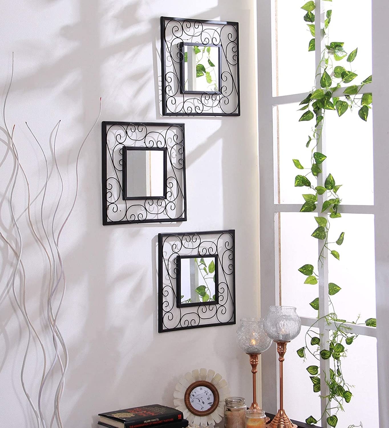 3 decorative mirrors are hung on a wall beside a window. 