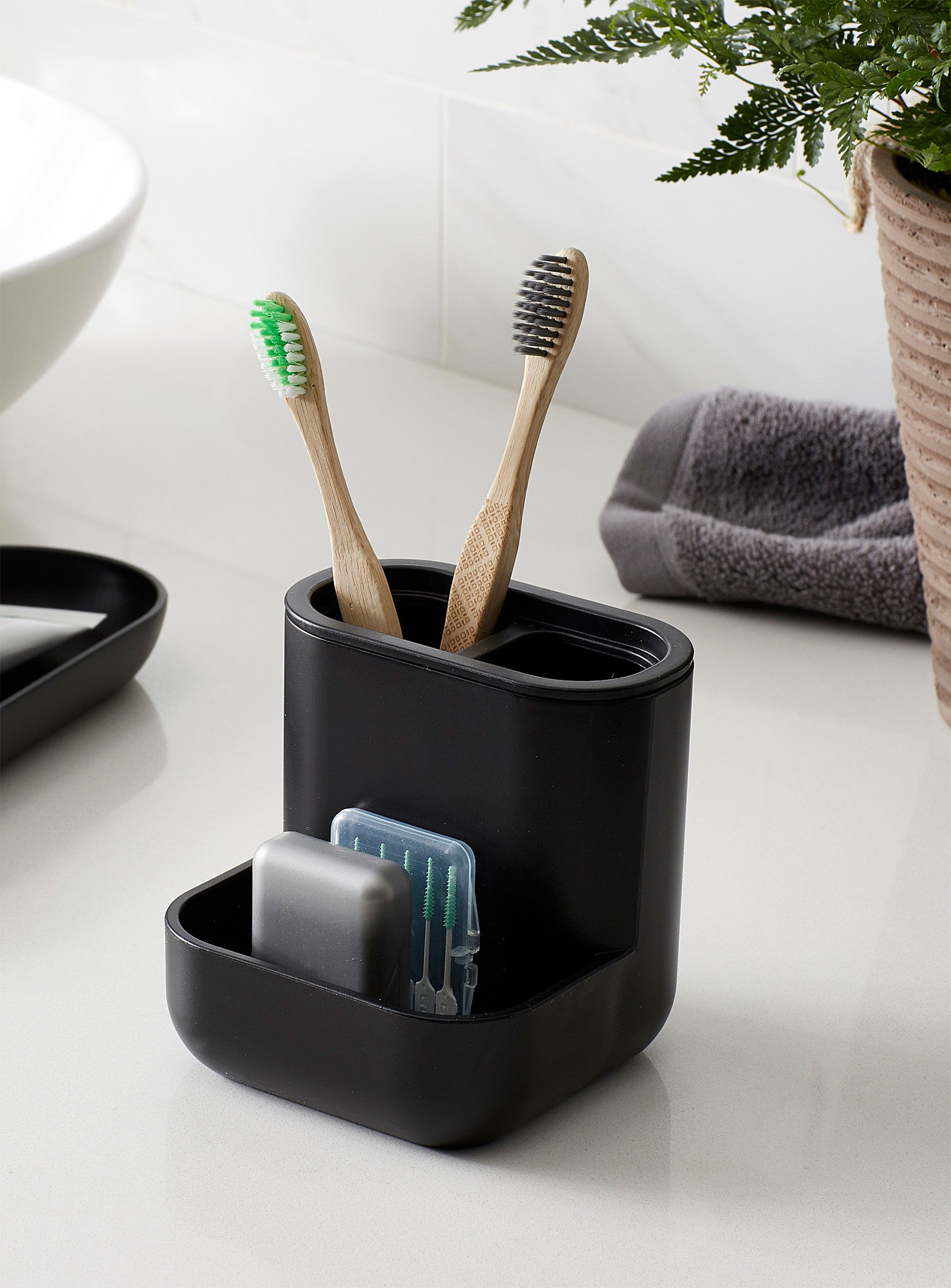 A plastic toothbrush holder with two toothbrushes in it