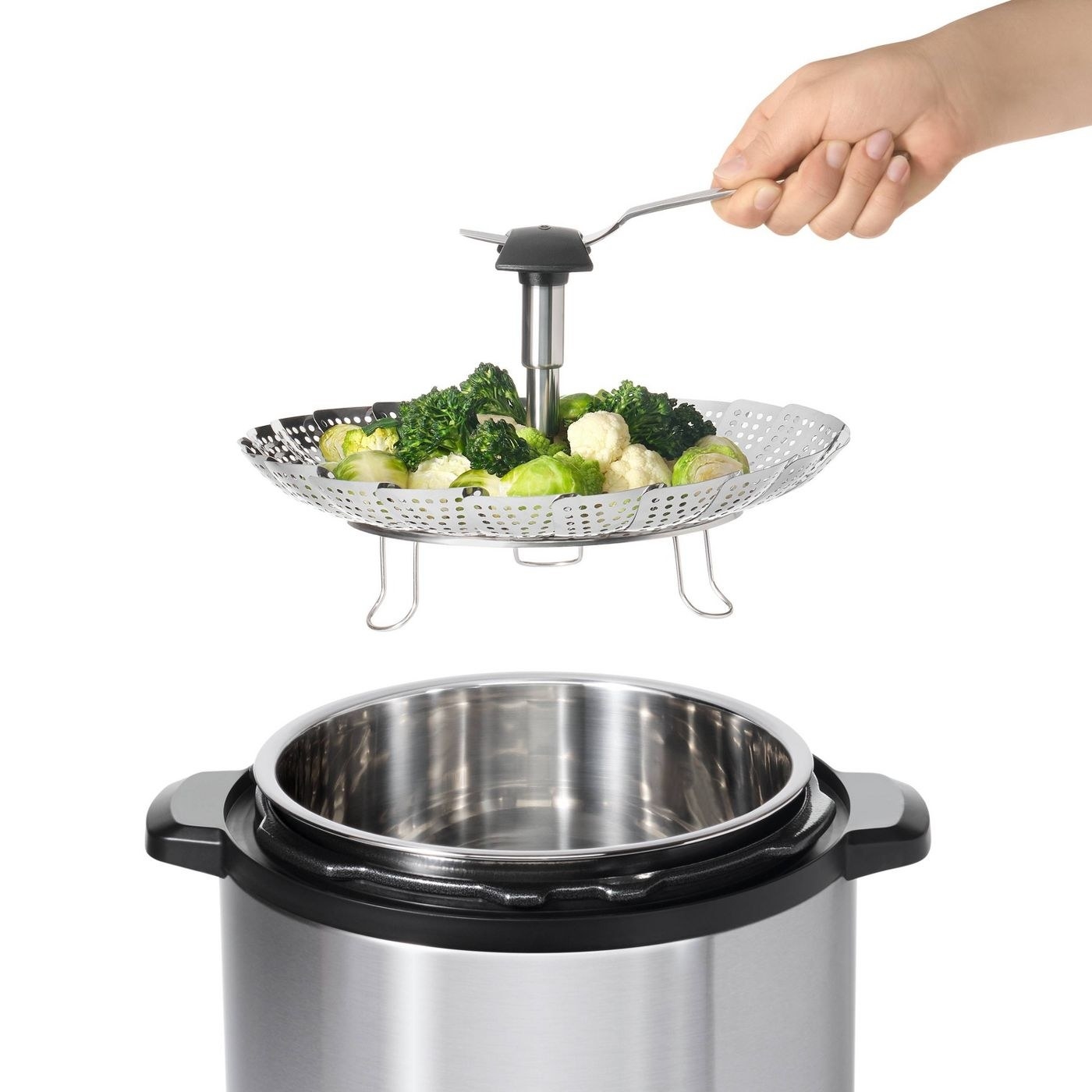 model holding a stainless steel steamer with vegetables over a pot of water