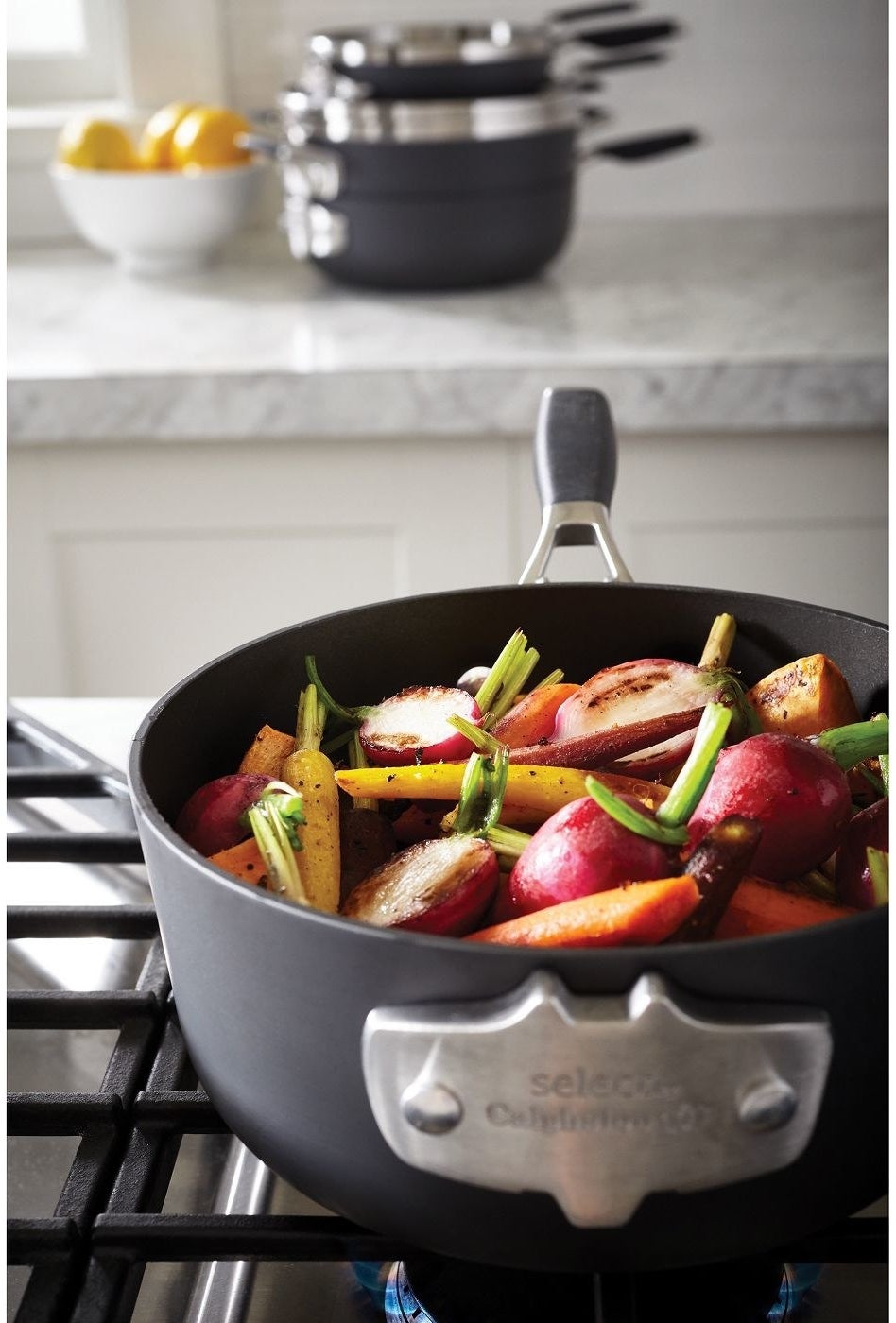 calphalon pot with vegetables inside and stackable pots and pans in the background