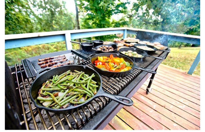 outdoor grill with several cast iron skillets cooking vegetables