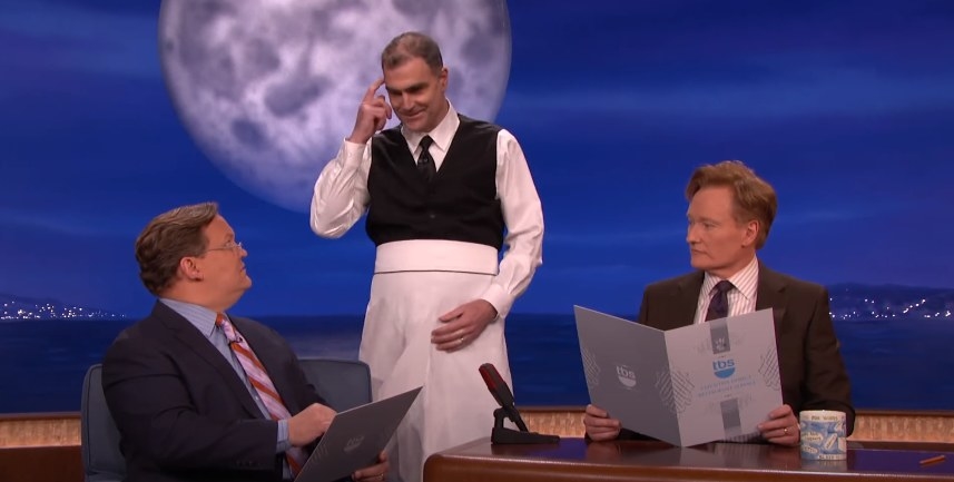 Conan and Andy Richter ordering food on set and a waiter listening