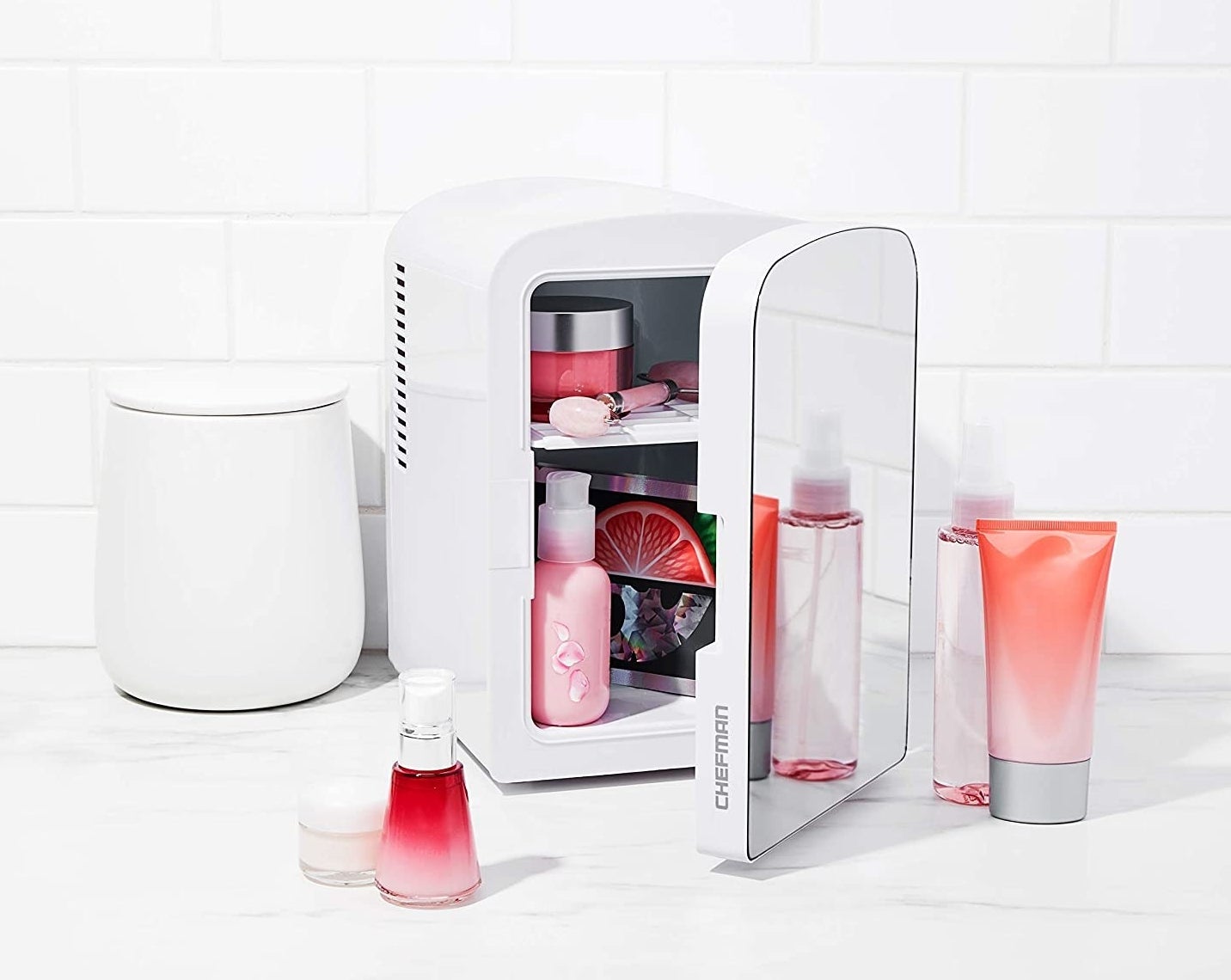 A mirrored mini fridge filled to the brim with skincare products