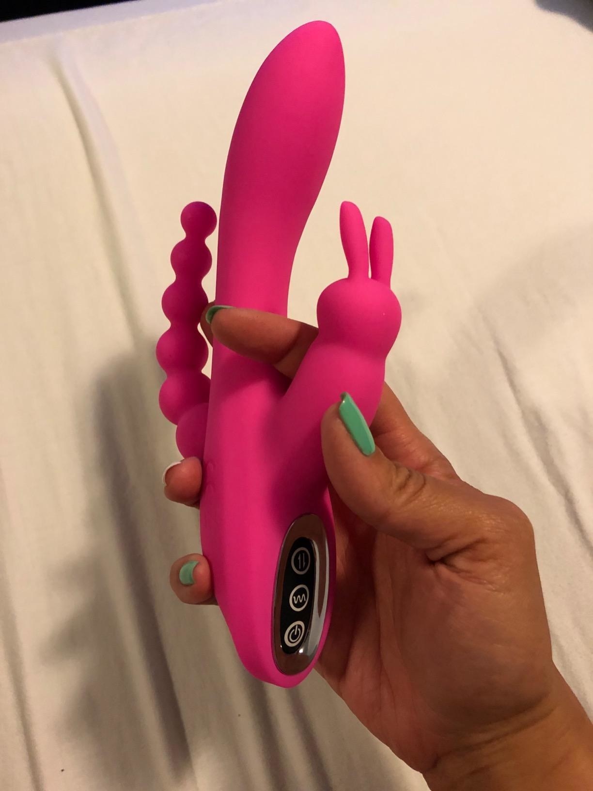 Model holding pink three-in-one rabbit vibrator to display clitoral stimulator, shaft and 