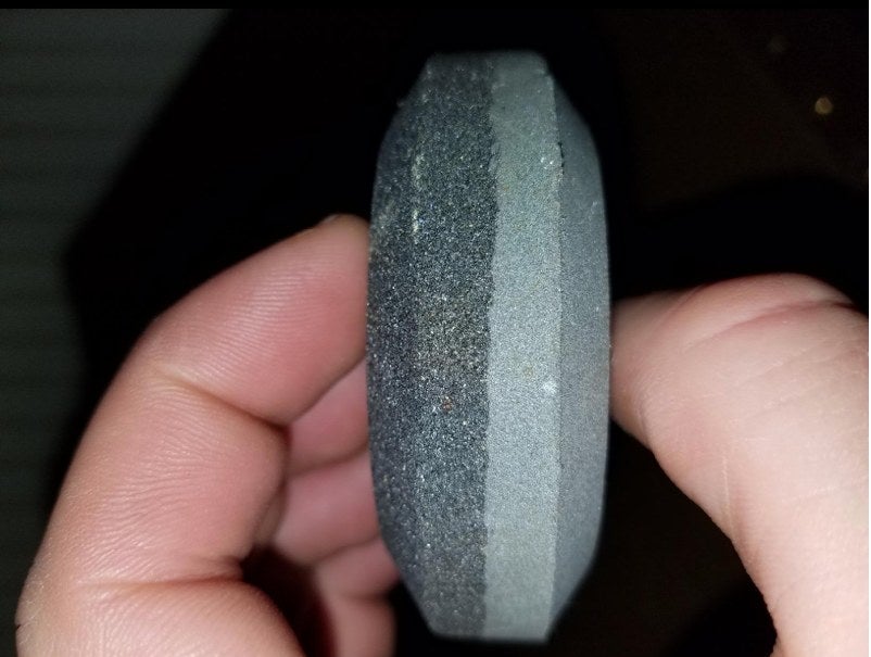 A reviewer holding a grey stone sharpening puck