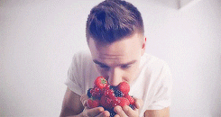 Liam Payne hold strawberries and looks up to the camera, very slowly