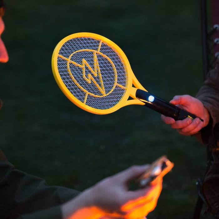 A person holding one of the electrified bug-zapping rackets