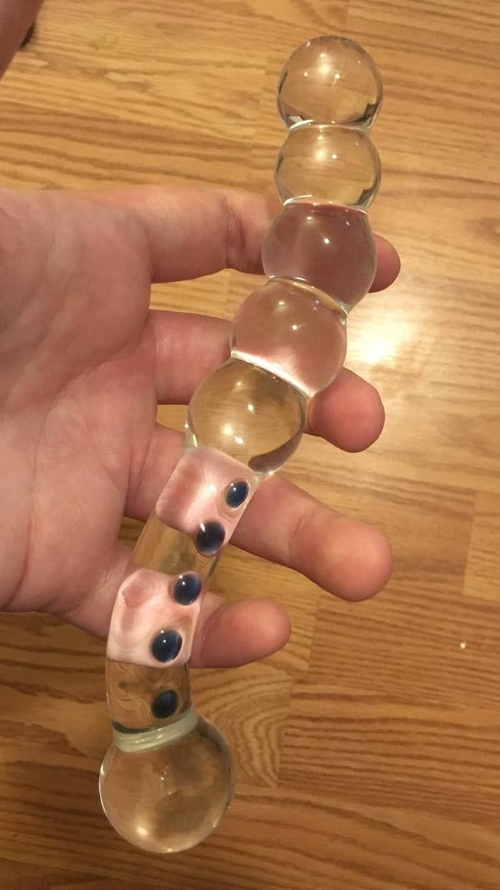 Model holding glass dildo with blue bead accents