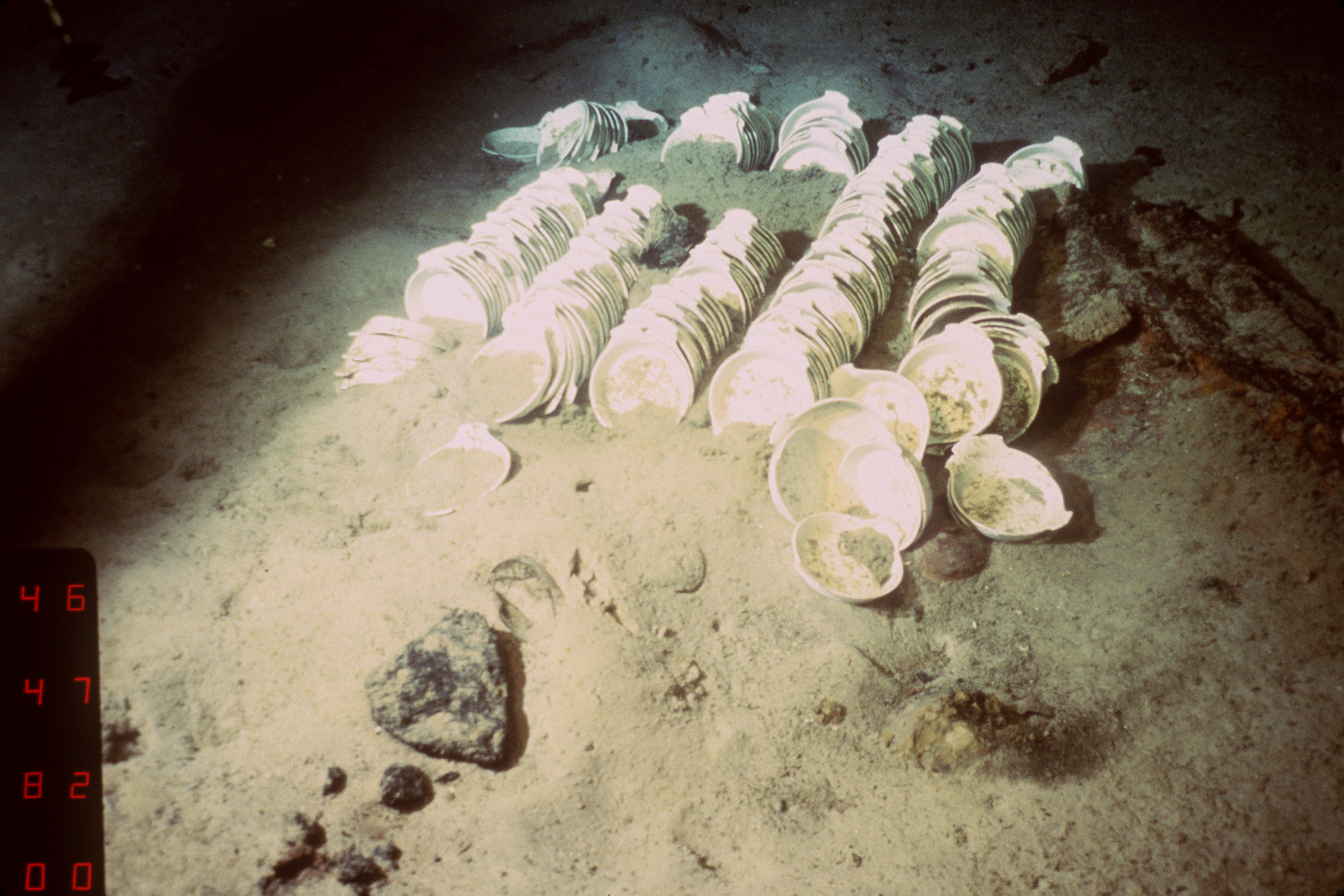 A dimly lit shot of stacks of dishes on the ocean floor