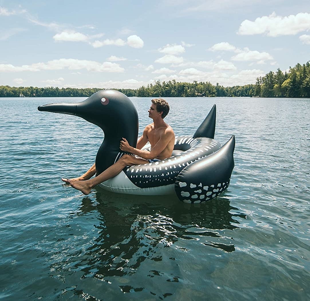 a person sitting on a loon-shaped float in a lake