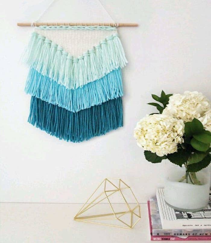 A tassel macrame wall hanging in 3 different shades of blue. 