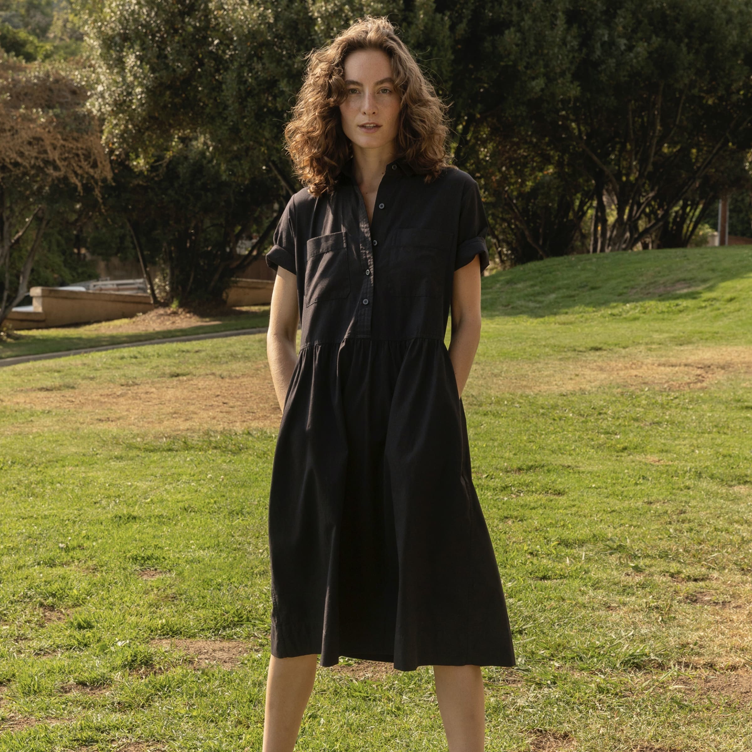 model wearing the black shirtdress while putting hands in pockets