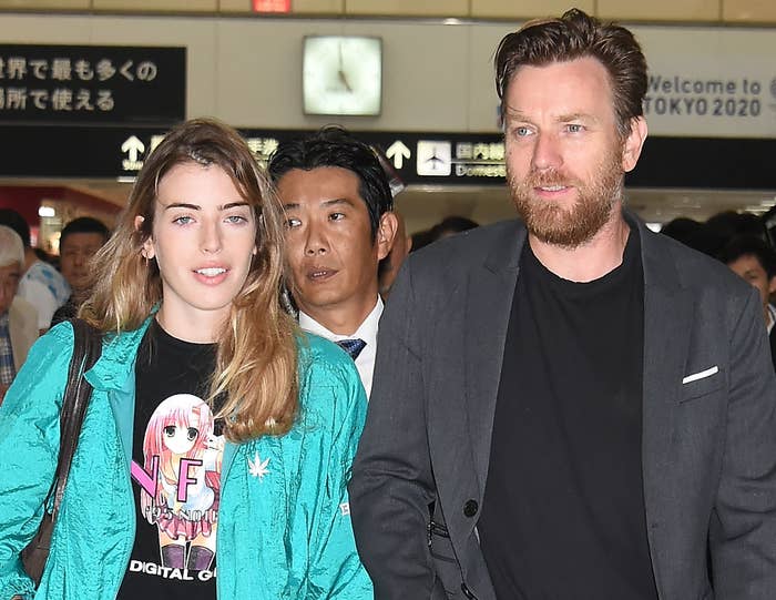 Clara and Ewan walk through an airport together