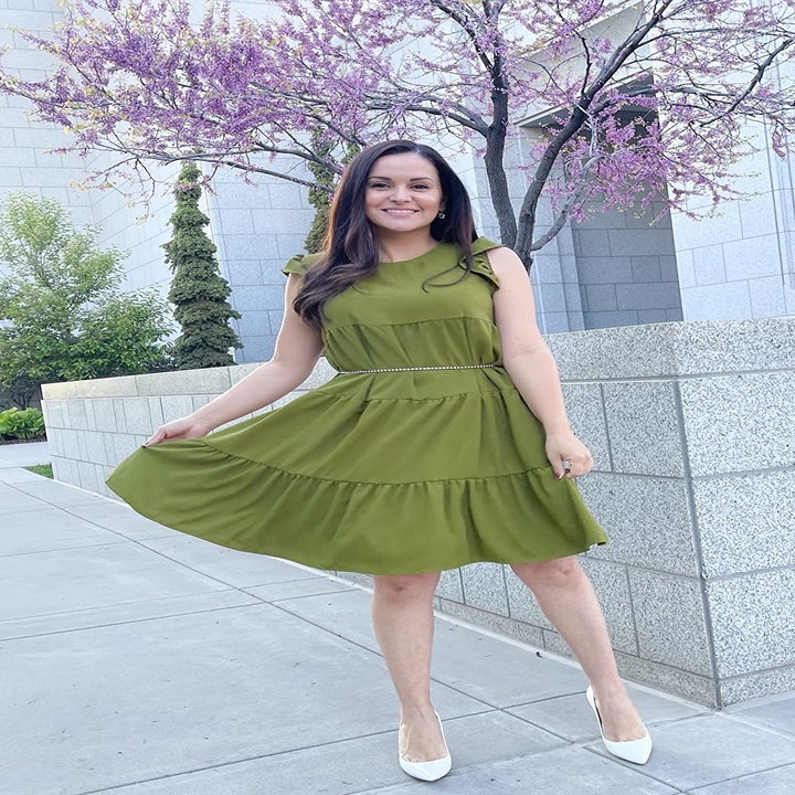 reviewer wearing the green tiered dress with a belt