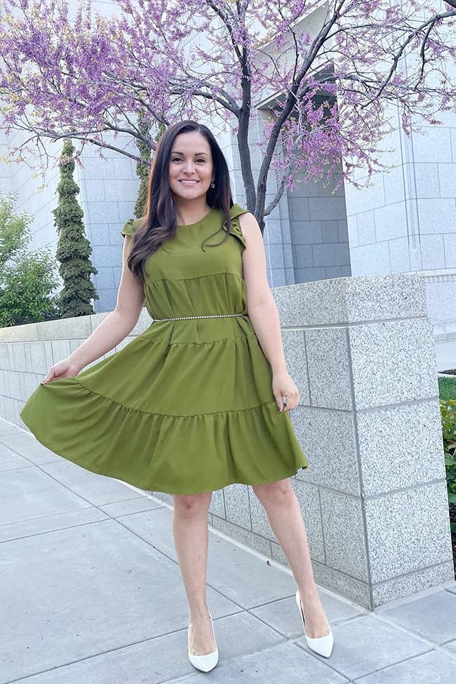 reviewer wearing the green tiered dress with a belt