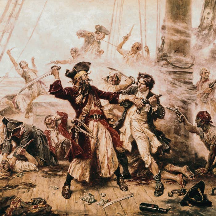 Pirates fighting on the deck of the ship with lots of people who are injured around them.