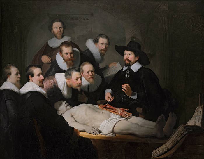 Renaissance painting of seven men in black shirts with white collars watching a doctor perform an anatomy on a dead man