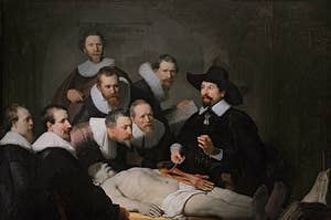 Renaissance painting of seven men in black shirts with white collars watching a doctor perform an anatomy on a dead man