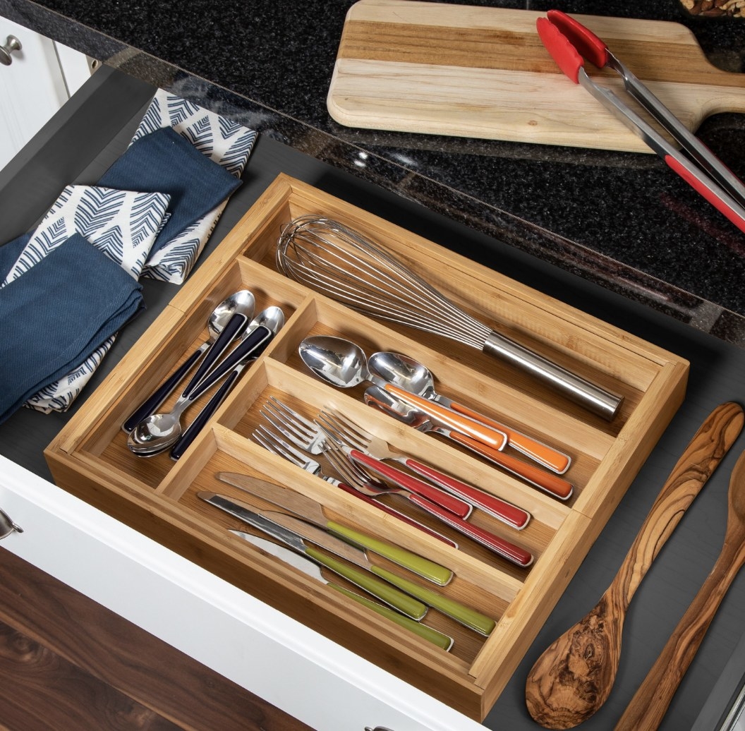 the wooden drawer organizer holding knives, forks, and spoons