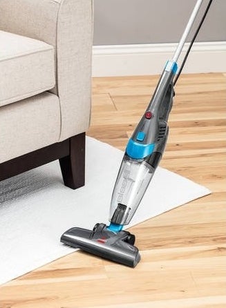 Stick vacuum being used on carpet and hardwood 