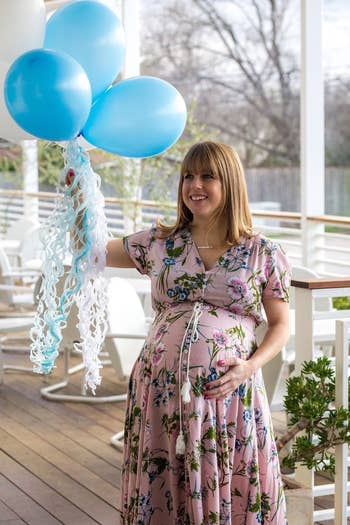 reviewer wearing the dress in pink while holding blue balloons
