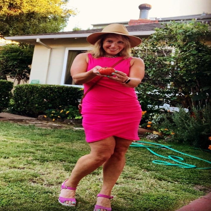 reviewer wearing the dress in pink while in a backyard