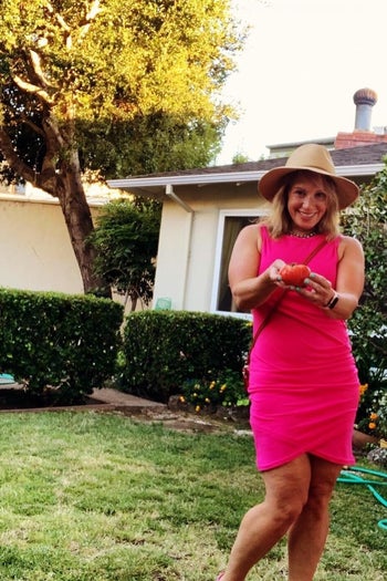 reviewer wearing the dress in pink while in a backyard