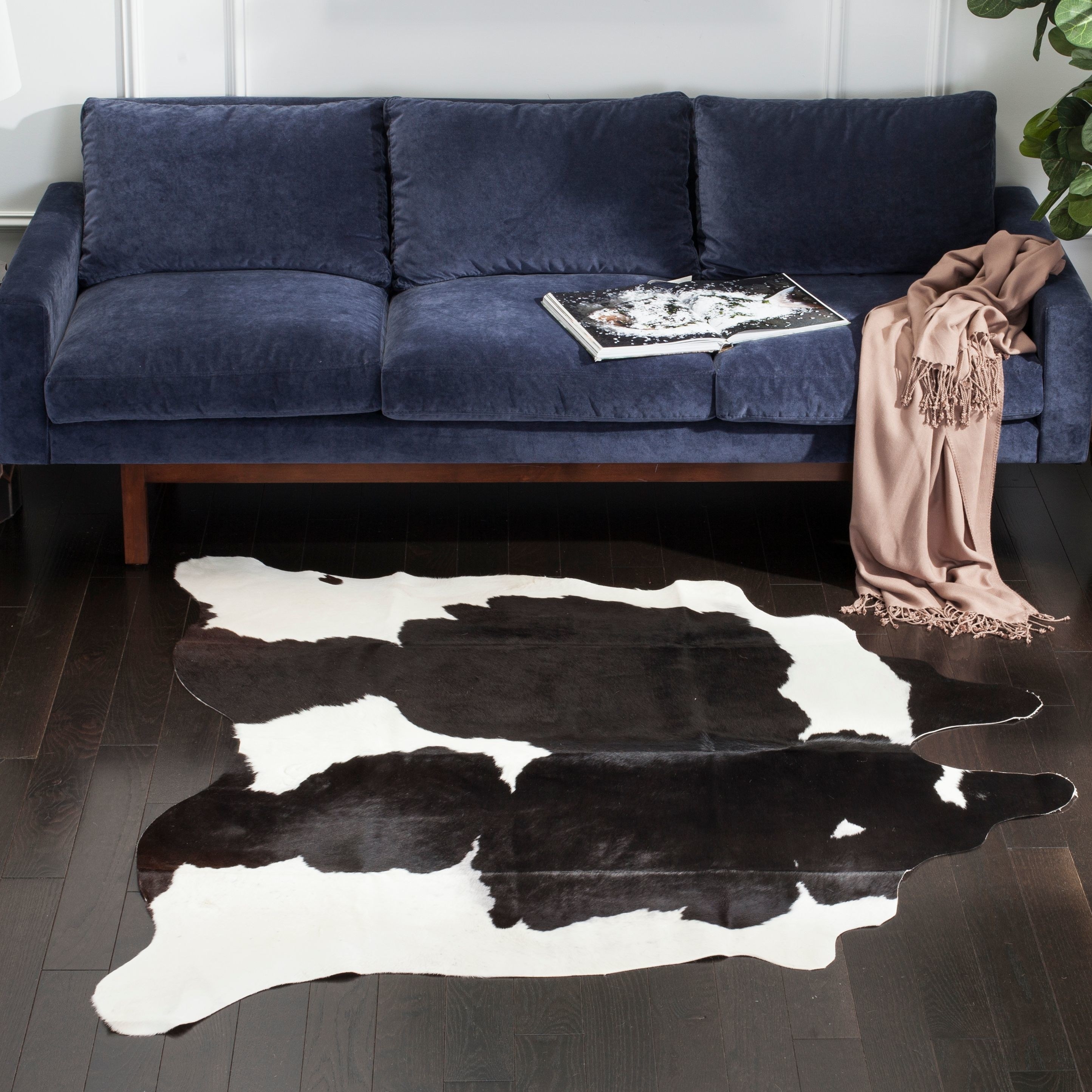 a navy couch and a black and white cow hide rug