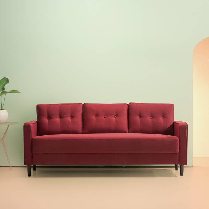 The long red couch with three tufted back cushions and square arms