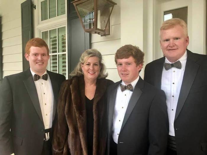 Three white men in tuxedos stand with a white woman in a fur coat