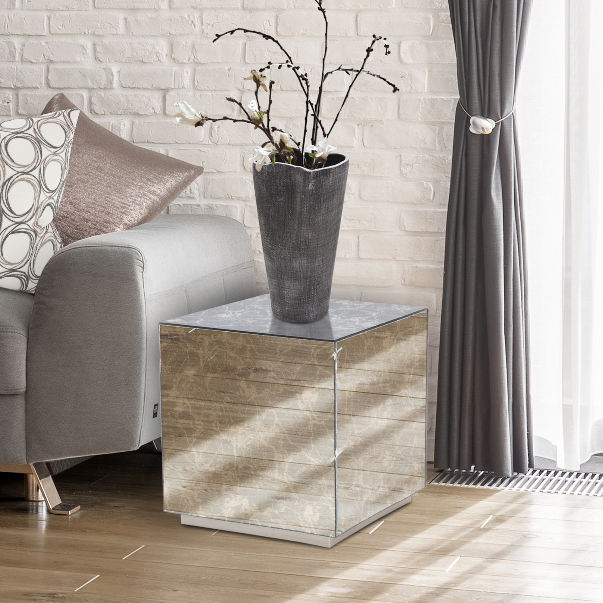 a mirrored end table next to a couch with a vase resting on top of it