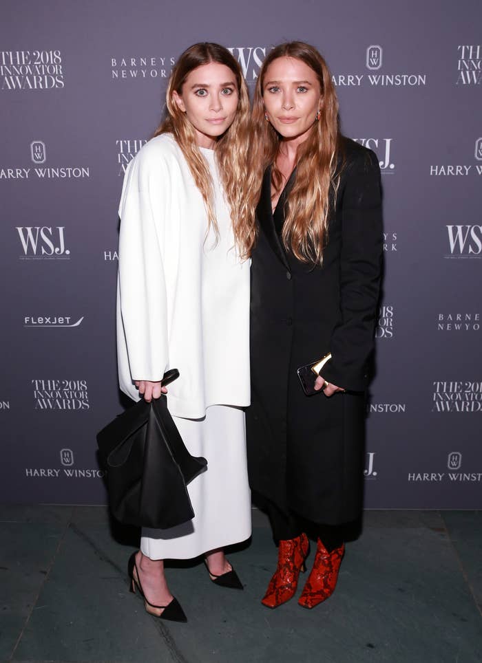 Ashley in a white dress and Mary-Kate in a black dress stand next to each other at the WSJ Magazine Innovator Awards in 2018