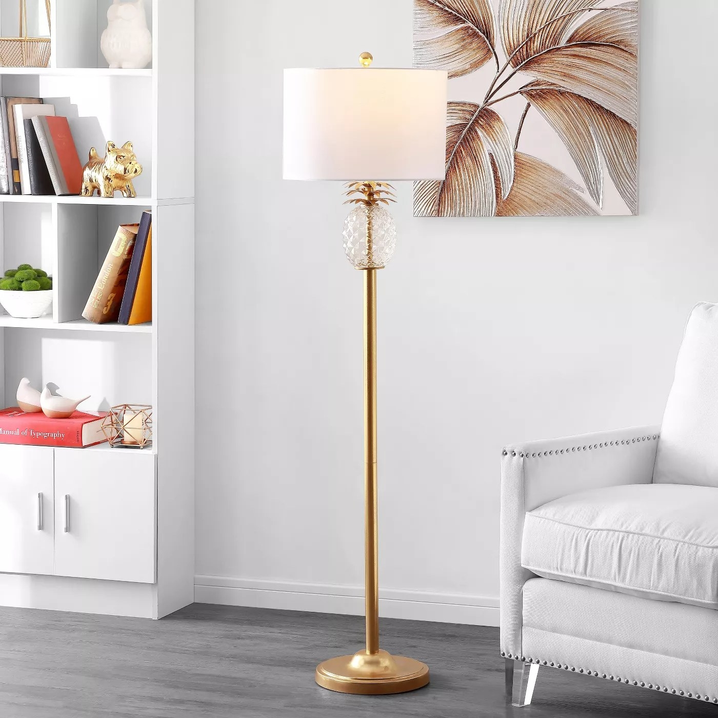 The gold floor lamp with a white shade and a glass pineapple