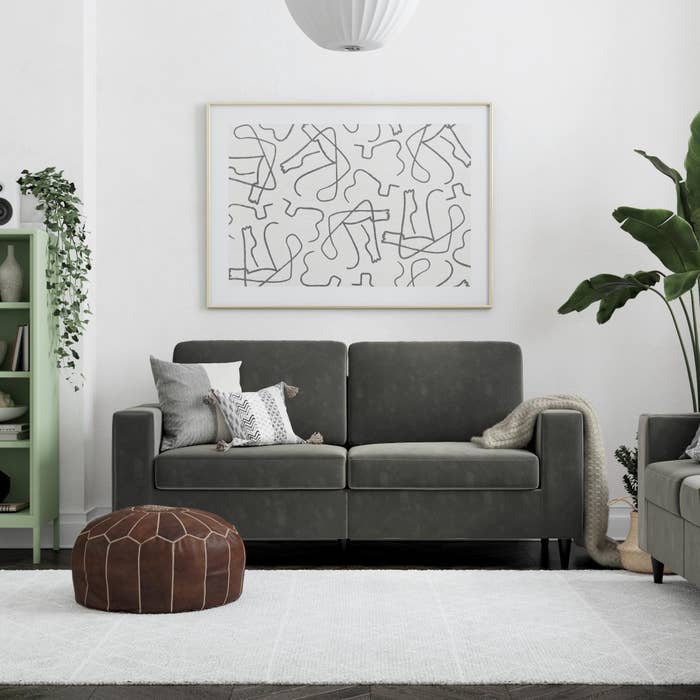 The gray velvet couch with two cushions and square arms in a living room
