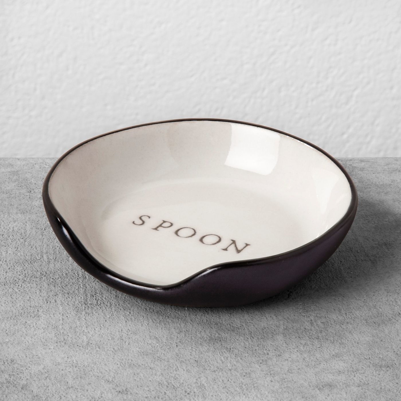 cream and black stoneware spoon rest with &quot;spoon&quot; engraved on the inside