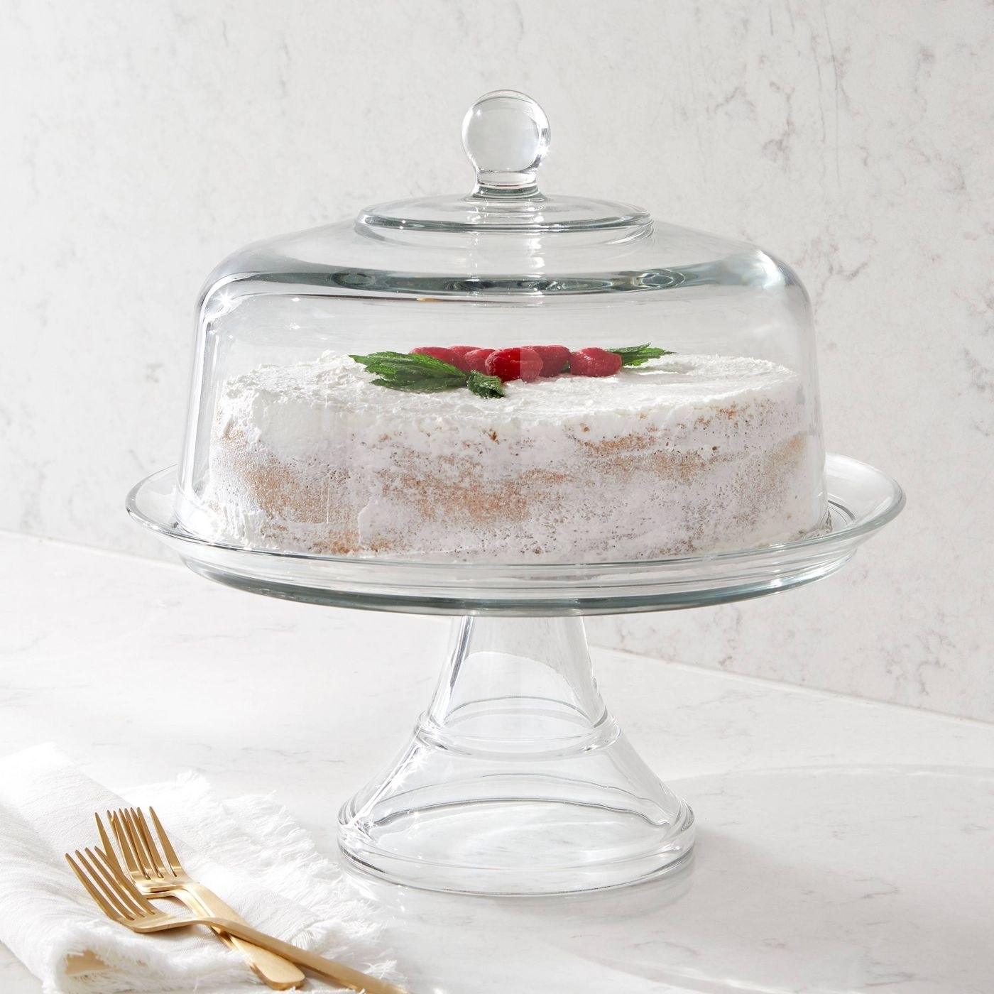 glass cake stand with lid and a cake inside