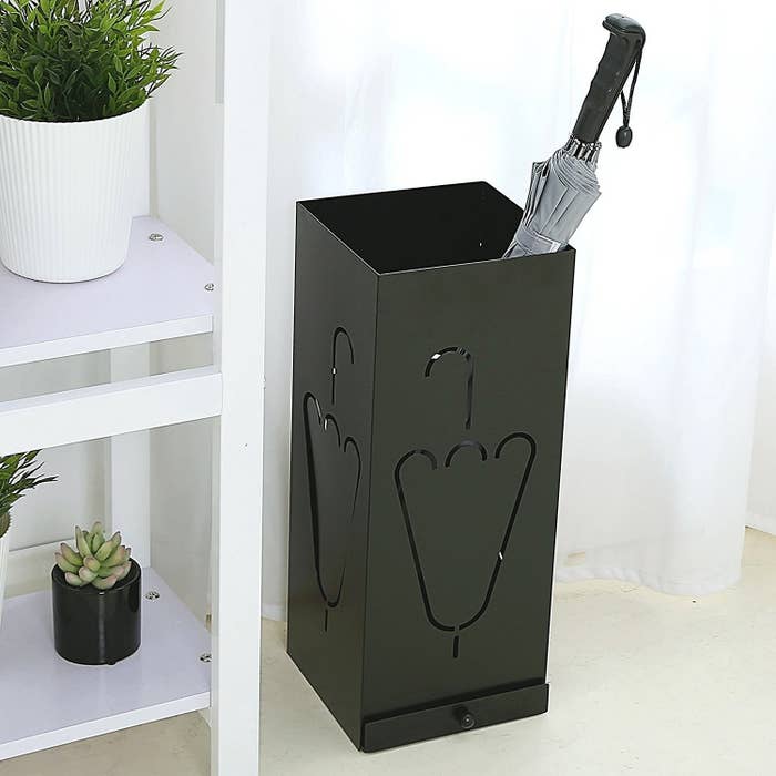 A black umbrella stand with an umbrella in it.